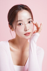 ピンク背景で撮影をした若い女性のキャッチーなビューティー...