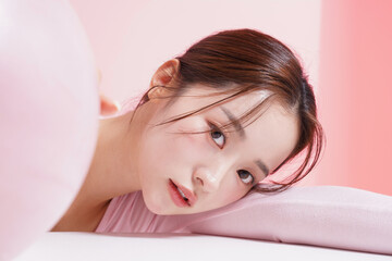 ピンク背景で撮影をした若い女性のキャッチーなビューティー...
