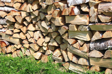 Cut firewood stacked outside. Background of wooden logs