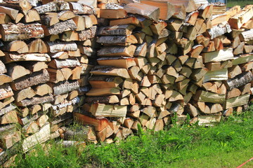 Cut firewood stacked outside. Background of wooden logs