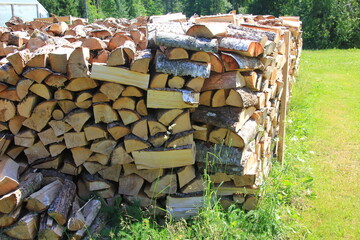 Cut firewood stacked outside. Background of wooden logs