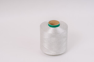A spool of fiberglass threads with a green core, placed against a plain white background, showcasing the detailed, tightly wound fibers.