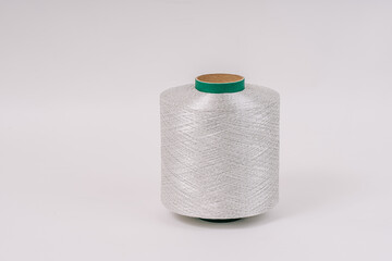 A spool of fiberglass threads with a green core, placed against a plain white background, showcasing the detailed, tightly wound fibers.
