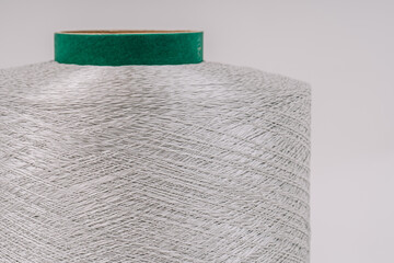 A close-up view of a large spool of fiberglass threads with a green core, showcasing the detailed and textured strands.