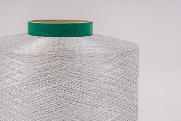 A close-up view of a large spool of fiberglass threads with a green core, showcasing the detailed and textured strands.