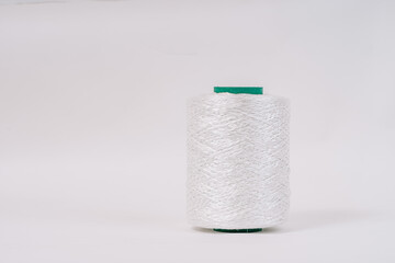 A spool of white fiberglass yarn with a green top, set against a white background. The image highlights the texture and coiling of the yarn.