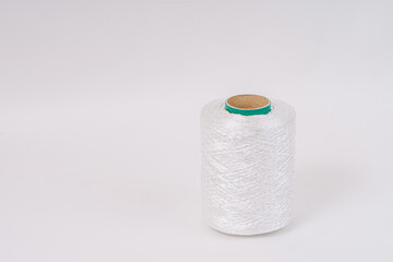 A spool of white fiberglass yarn with a green top, set against a white background. The image highlights the texture and coiling of the yarn.