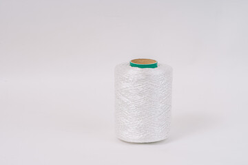A spool of white fiberglass yarn with a green top, set against a white background. The image highlights the texture and coiling of the yarn.