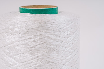 Close-up of a spool of white braided fiberglass yarn with a green core, showing the texture and pattern of the material.