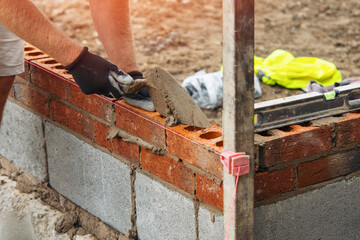 Construction Worker Laying Brick and Mortar for Wall at Building Site During Daylight Hours