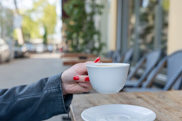 Person Enjoying Cup of Coffee at Cozy Outdoor Café on Sunny Day
