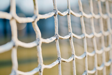 Fototapeta premium close-up of a sports net, showcasing its texture and structure with a blurred, out-of-focus sports field in the background