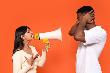 Woman Uses Megaphone to Communicate With Man Who is Covering His Ears Against Bright Orange...