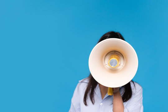 Person Holding Megaphone Against  Blue Background, Likely Encouraging or Announcing Something