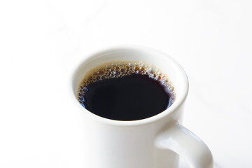 淹れたてのコーヒーが入った白いマグカップ
