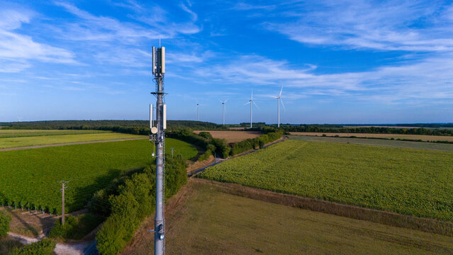Rural Telecommunication Tower Amid Expansive Farmland and Wind Turbines and 5G - Powered by Adobe