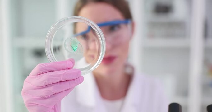 Scientist observes microbial growth in Petri dish in lab. Female researcher detects alterations or variations in sample to understand implication