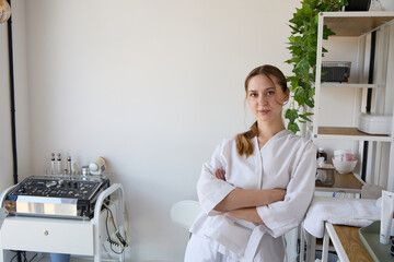 Confident female esthetician standing in modern skincare clinic