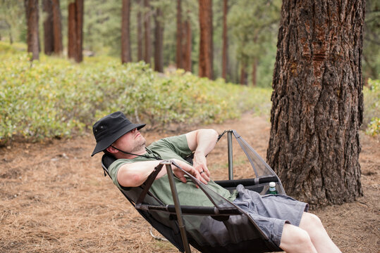 Man resting in a camping chair in the woods
