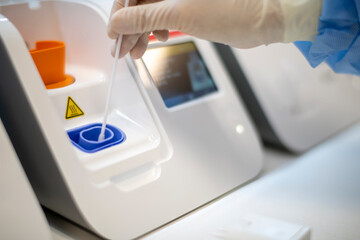 Lab technician placing swab into point-of-care testing machine f