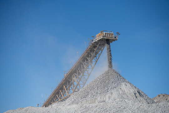 Industrial conveyor belt dumping rocks at a copper mine with bri