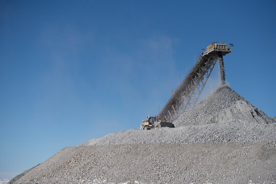 Industrial conveyor belt dumping rocks at a copper mine with bul