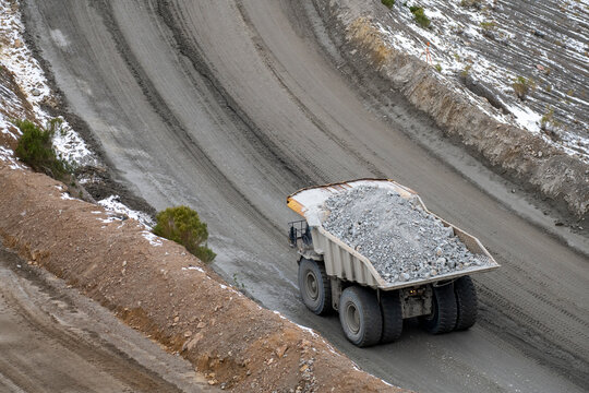Large scale industrial dump truck full of rocks driving on a min