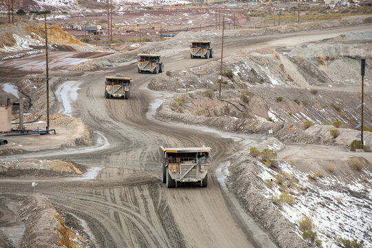 Four large scale industial heavy duty haul trucks driving on min