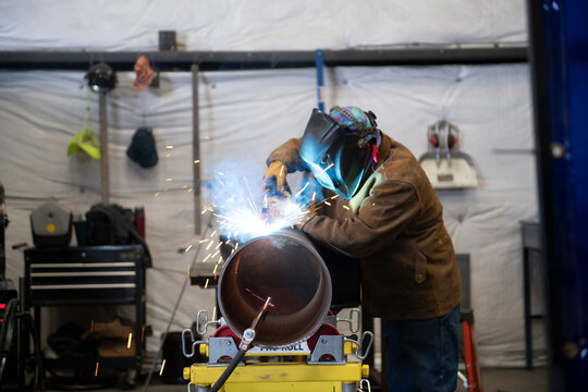 Welder working on a section of industrial pipe in his repair wor - Powered by Adobe