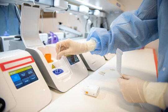 Lab technician placing swab stick into point-of-care testing mac