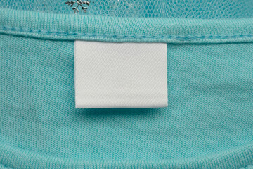 White blank laundry care clothes label on blue shirt fabric background