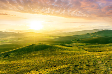 Obraz premium spring green field landscape in beautiful countryside with green and yellow grass, rural hills and amazing cloudy sky on background. Agriculture landscape with rural view