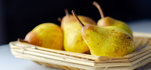 A basket of pears with a few of them still attached to their stems