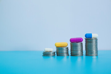 Colorful capsules are on growth coin stack symbolizing health insurance, medical expenses and medicine, finance, saving money, business, Financial and medical. Medicine Scattered on pile of coins.
