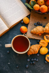 Cup of tea, open book, apricots and blueberries, summer mood