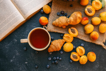 Cup of tea, open book, apricots and blueberries, summer mood