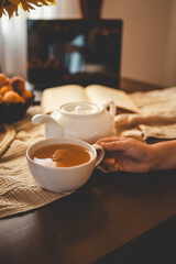 Cup of tea, open book and laptop on the table, evening summer mood