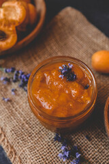 Homemade apricot jam with lavender flowers, surrounded by fresh apricots and lavender sprigs on a rustic burlap cloth