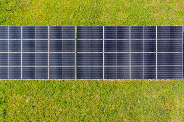 Aerial View of Solar Panels in a Field of Green Grass.