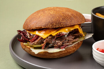 Portion of brisket burger with potato wedges on green background