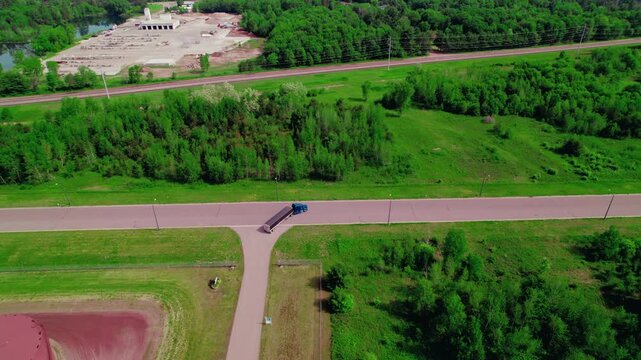 Blue semi truck with hopper trailer taking right turn. Beautiful aerial view.