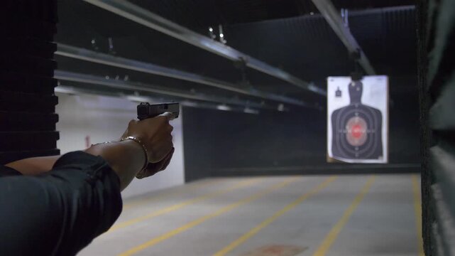 Shooting range practice. Woman practicing with firearm handgun shooting at indoor targets.