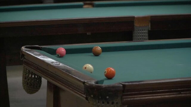 Slow-motion view of a ball pink 4-ball pushed into a corner pocket during a pool game.
