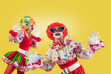 Funny clowns, nan and woman entertainers dressed as a colorful Joker in a suit and wig, with clown...
