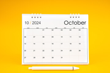 October 2024, Monthly desk calendar for 2024 year and pen on yellow background.