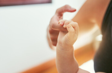 Mother, baby and hand holding with love at house for playful care, family bonding and nurture support of connection. Woman, infant and fingers for security, emotional touch and growth of development