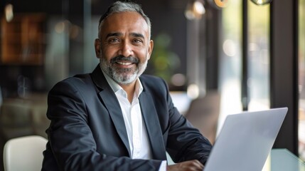 Fototapeta premium A man in a suit is sitting at a table with a laptop in front of him