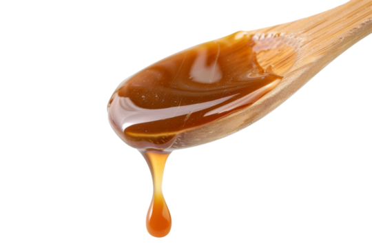 Close up of Spoon with Caramel sauce liquid dipping isolated on background, sweet sugar sauce for dessert.