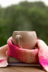 Autumn mood with a mug of hot tea against the backdrop of nature. Tea, steam, knitted scarf and...