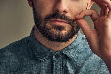 Man, face and twirl mustache in studio for grooming, haircare and styling on dark background. Male...
